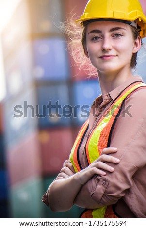 Young confident Caucasian woman engineer wearing yellow safety helmet and check for control loading containers box from Cargo freight ship for import and export