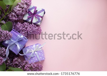 colorful modern gift boxes with lilac on pink background. presents with flowers