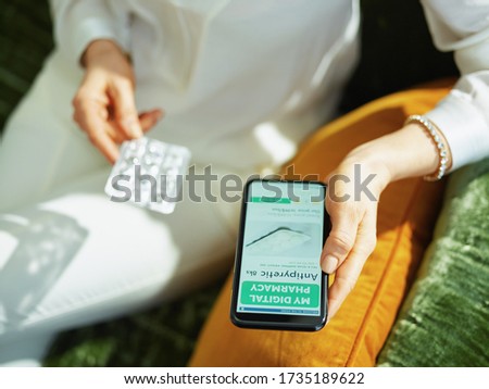 Closeup on woman with empty blister pack of pills buying pharmacy online using smartphone in the house in sunny day.