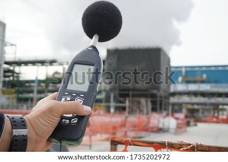 Hand of Environmental officer holding to use sound level meter for monitor is part of the prevention of environmental impacts at Chemical plant area or refinery factory. Royalty-Free Stock Photo #1735202972
