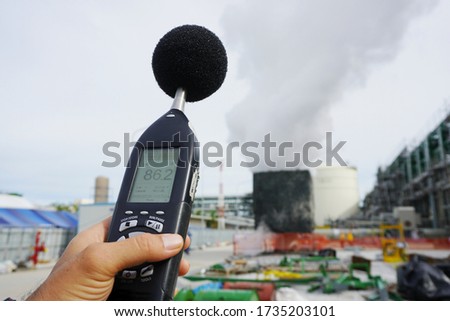 Hand of Environmental officer holding to use sound level meter for monitor is part of the prevention of environmental impacts at Chemical plant area or refinery factory. Royalty-Free Stock Photo #1735203101