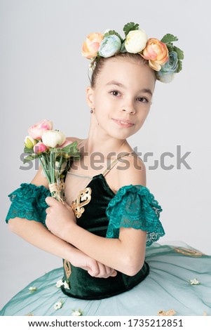 Delicate girl close up portrait posing with flowers in her hair and hands with a charming smile on white background
