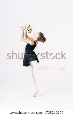 Beautiful girl ballerina dancing with flowers wearing a black tutu on white background