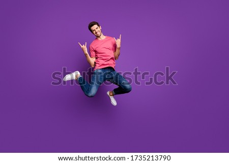 Full size photo of cheerful crazy guy heavy metal music concert lover enjoy rejoice jump show horned symbol wear casual style clothes sneakers isolated over bright shine color background