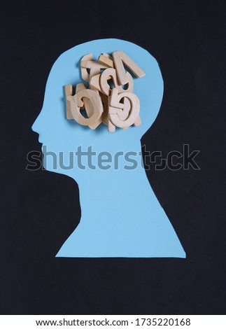 Human head shaped from paper cut and wooden letters of alphabet on top of blue background