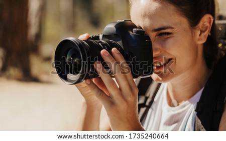 Closeup of a female taking photographs of the landscape with a digital camera. Woman photographer filming scenery with a professional camera.
