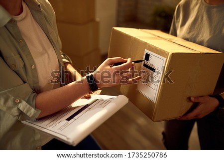 Two delivery women cooperating while checking data on the packages in the office.  Royalty-Free Stock Photo #1735250786