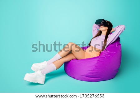 Full size profile photo of relaxed lady sit comfy bean bag chair watch innovation game vr glasses hands behind head wear sweater orange skirt shoes socks isolated teal color background