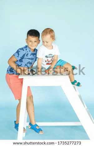 two brothers playing with toys. Brothers friendship. Two kids in studio isolated on blue looking into camera. family concept.