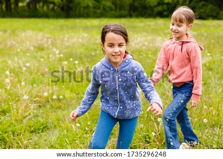 Two adorable girls dancing on the meadow