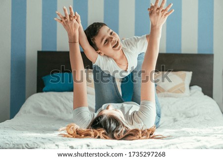 selective focus of mother lying on bed and holding hands with toddler son while playing in bedroom
