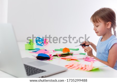 Portrait of little girl cutting a paper make art craft activities stay at home from Coronavirus covid-19 crisis. Child cutting paper with scissors online learning. homeschooling kid.