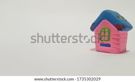 A miniature photo of a toy house made of painted clay. White background.