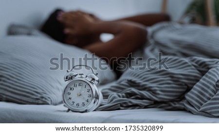 African american woman suffering from insomnia lying in bed without sleep with alarm clocks close up, panorama Royalty-Free Stock Photo #1735320899