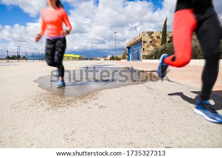Fast young couple running on a road outside over a puddle with motion blur