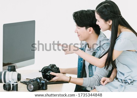 Asian Photographer and female model looking pictures in computer monitor on desktop