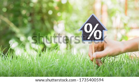 People are putting house signs with interest symbols with place pins and green grass. The concept of buying a house with interest. planning savings money of coins to buy a home concept for mortgage.