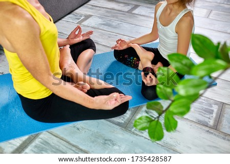 Mother and her daughter doing yoga together at home.