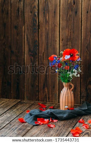 Wildflowers in a clay vase on a wooden table, a bouquet of poppies, still life