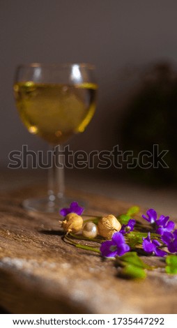 Still life from a glass of lemonade on the table with small flowers of green, purple and yellow under powdered sugar.