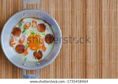 close up image of egg pan decorated by sausage, crab stick and spring onion put on the bamboo plate for break fast: top down view.