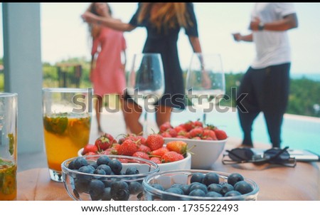 Blurred background with people enjoing party and drinks with berryies on foreground