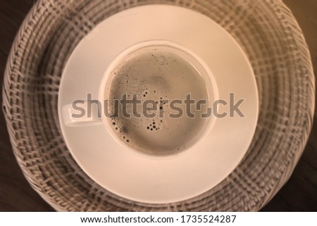 Top view of black coffee in a white mug with saucer Placed in the deck ready to be served, The picture tone has the characteristics of colour and light that give a warm feeling.