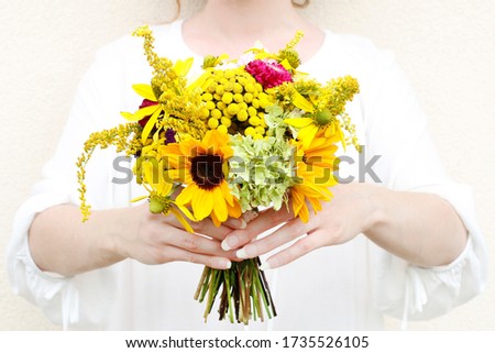 Young woman is holding a bouquet of lovely yellow summer flowers. 
