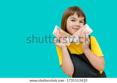 a girl of 8 years of Asian appearance holds in her hands banknotes of 10 thousand Russian rubles on an isolated background finance theme Royalty-Free Stock Photo #1735553420