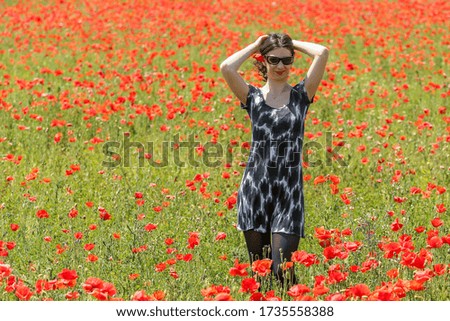 Portrait of beautiful young girl in poppies field outdoor. Blooming Poppies memory symbol.