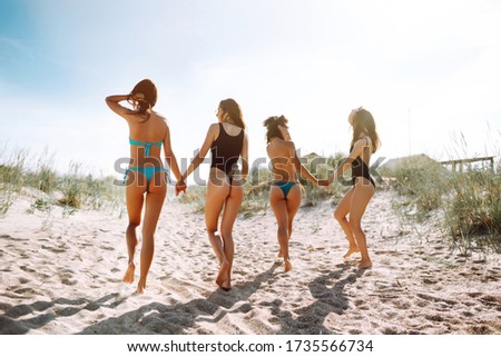 Happy  four girls strolling along a beach. Young women enjoying on beach holiday. Summer, relax and lifestyle concept.