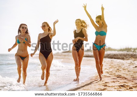Happy four girls having fun on the beach. Young women enjoying on beach holiday. Summer, relax and lifestyle concept.
