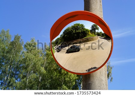 Road round mirror. Mirror to help transport. Help cornering. Red round mirror on a post. Road mirror on a background of blue sky. Give Way. 