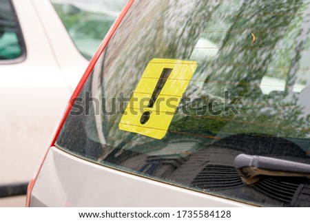 A yellow exclamation mark on the rear window of a car. Inexperienced driver concept. Sign of an inexperienced driver Royalty-Free Stock Photo #1735584128