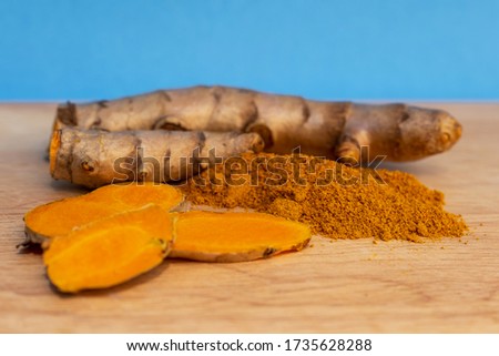Picture of Turmeric root and turmeric powder on a blue background.