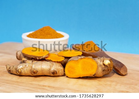 Picture of Turmeric root and turmeric powder on a blue background.