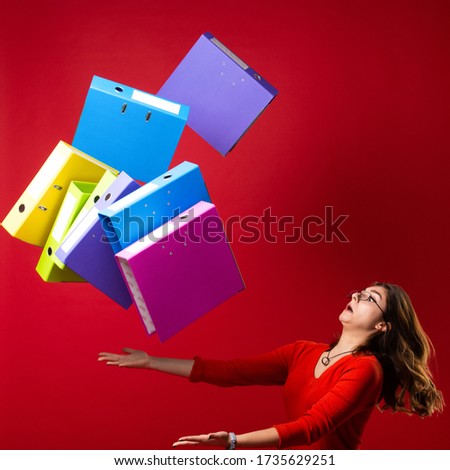 The girl in glasses throws up folders, with a fright on her face on a red background. Mood stress, panic, accounting reporting, tax audit, exams