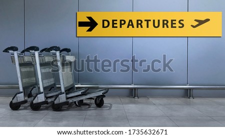 Airport Sign for Departures Terminal Directory inside the Building. Travel and Transportation Concept. Blurred Baggage Carts as foreground
