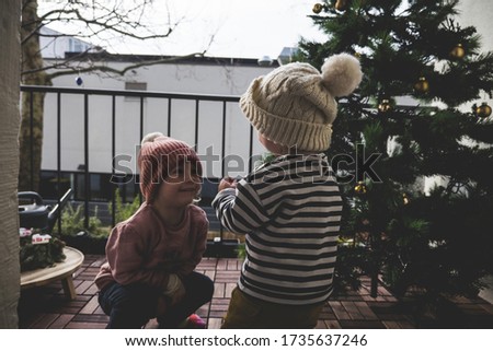 The two little kids in knitted hats decorating the Christmas tree