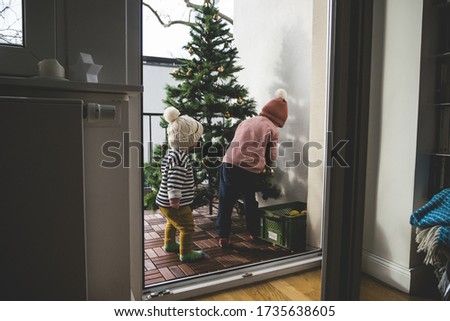 The two little kids in knitted hats decorating the Christmas tree