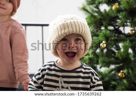A shallow focus shot of a cute little smiling baby in a white knitted winter hat