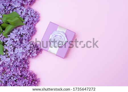 Beautiful spring lilac flowers and gift present box on light pink background. Flat lay top view picture with copy space