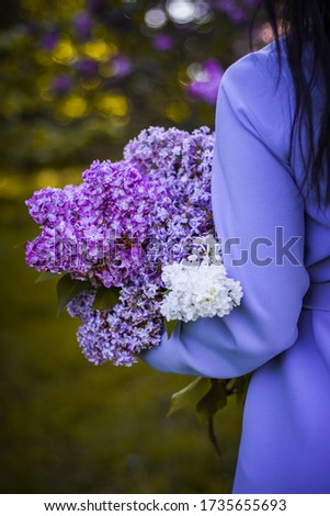 bouquet of lilac flowers in the hands of a young girl with black hair