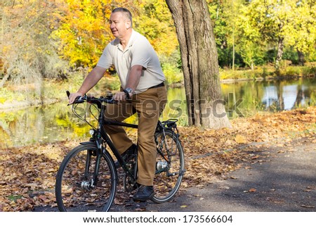 Man rides his bike through the park in autumn