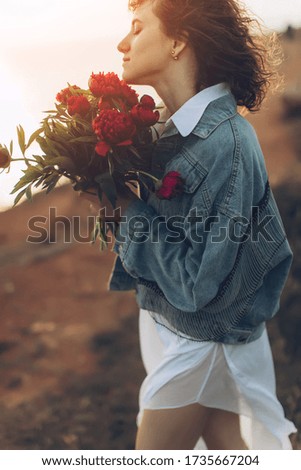 Beautiful girl in a hat on nature with a bouquet of peonies.