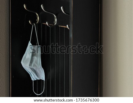 The New Norm. Face mask hangs near the front door during quarantine. Royalty-Free Stock Photo #1735676300
