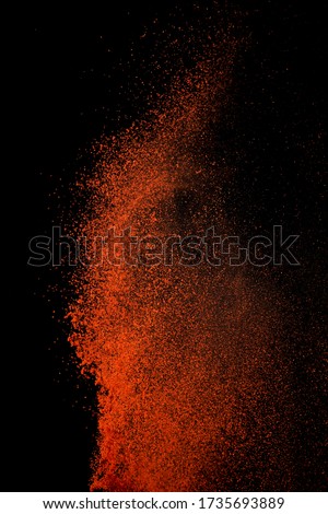 Red paprika spices powder explosion, flying chili pepper isolated on black background. Splash of spice background. 