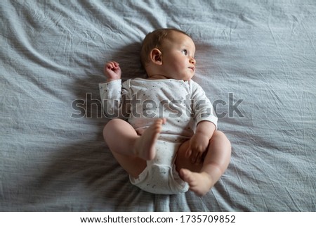 Authentic shot of a cute curious newborn baby  boy is lying on the bed and looking around.
