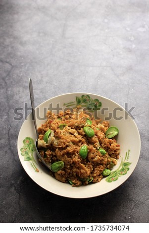 Nasi Goreng Pete, Fried Rice with Stinky Beans on a White Plate. Isolated Picture on Rustic Cement Background