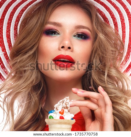 Bright cheerful girl in a summer hat, colorful make-up, curls, pink manicure and ice cream in the hands. Beauty face. Photo taken in the studio.